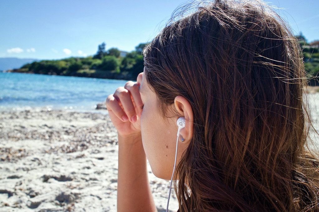 photo of girl listening to music on the beach