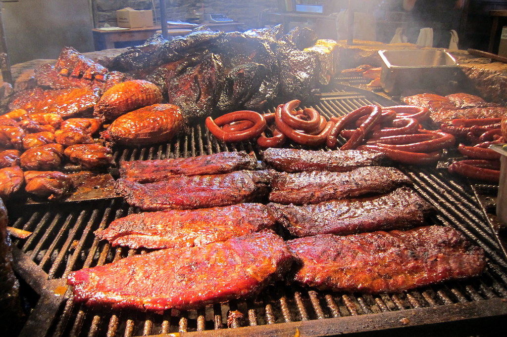 A large barbecue grill with steaks, sausages, and other meats